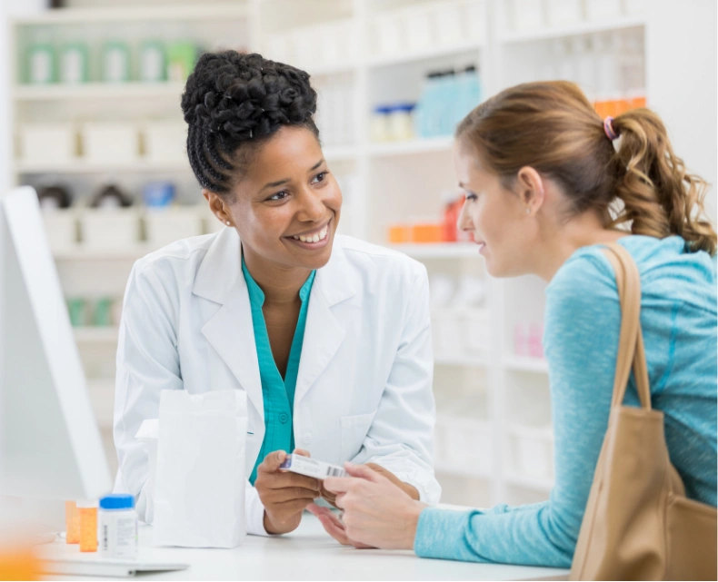 Pharmacist smiling and helping a customer at the pharmacy counter.